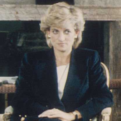 Princess Diana wearing a black blazer and skirt sitting in a chair