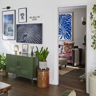 open plan living space with green storage unit under artwork gallery wall