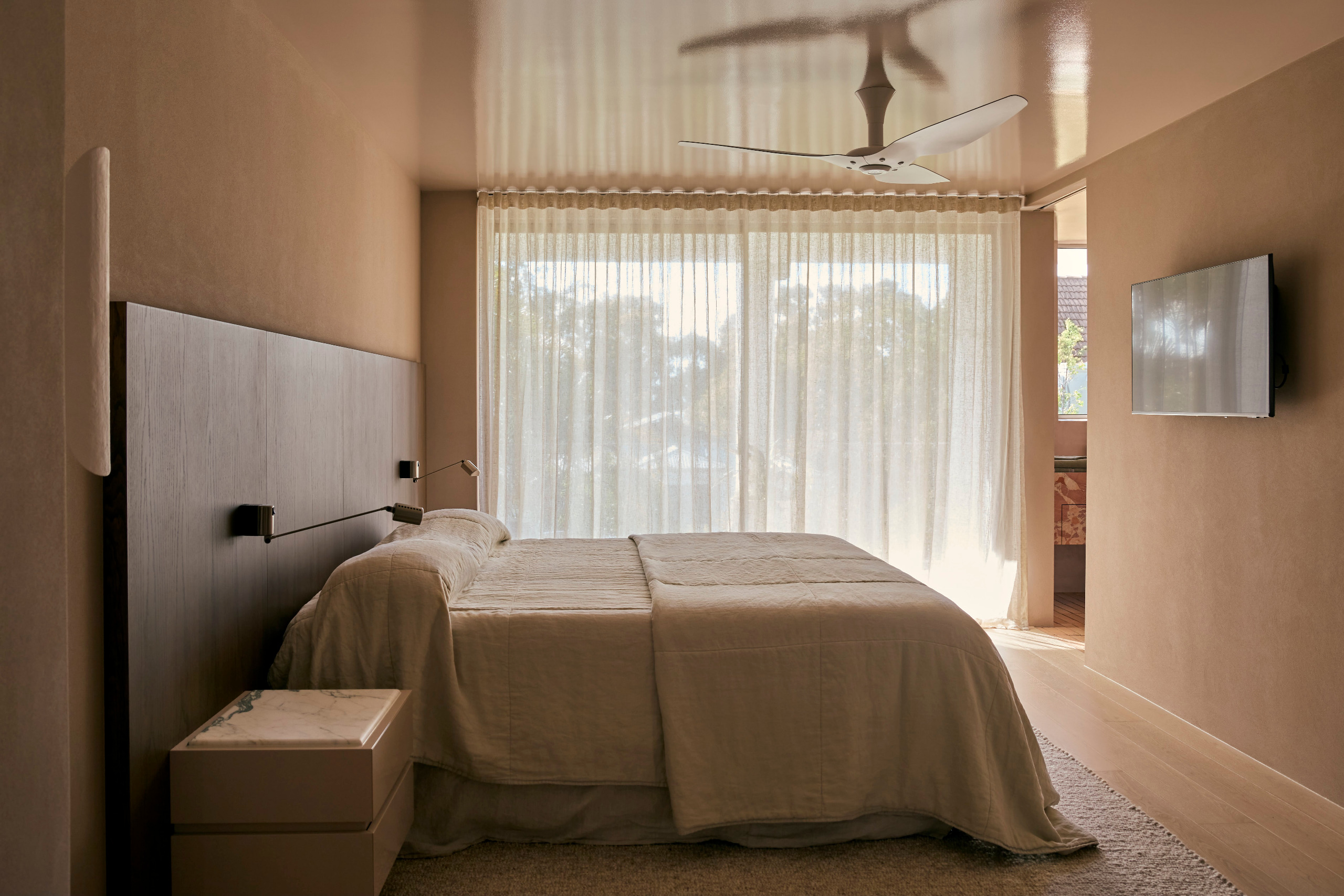 A biscuity pink/brown color-drenched bedroom with high-gloss ceiling