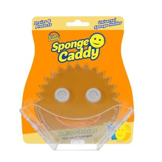 A clear Scrub Daddy holder on an orange curved piece of cardboard that says 'Sponge Caddy' on it