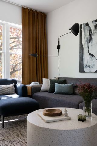 living room with white walls, grey sofa with colored throw pillows and art