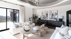 Minimal neutral living room with art on walls, circular coffee tables, accent pendant light, and cream couches