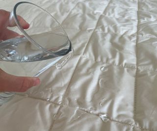 Woolroom Deluxe Washable Mattress Protector having water poured over it