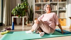 Senior woman sits on exercise mat