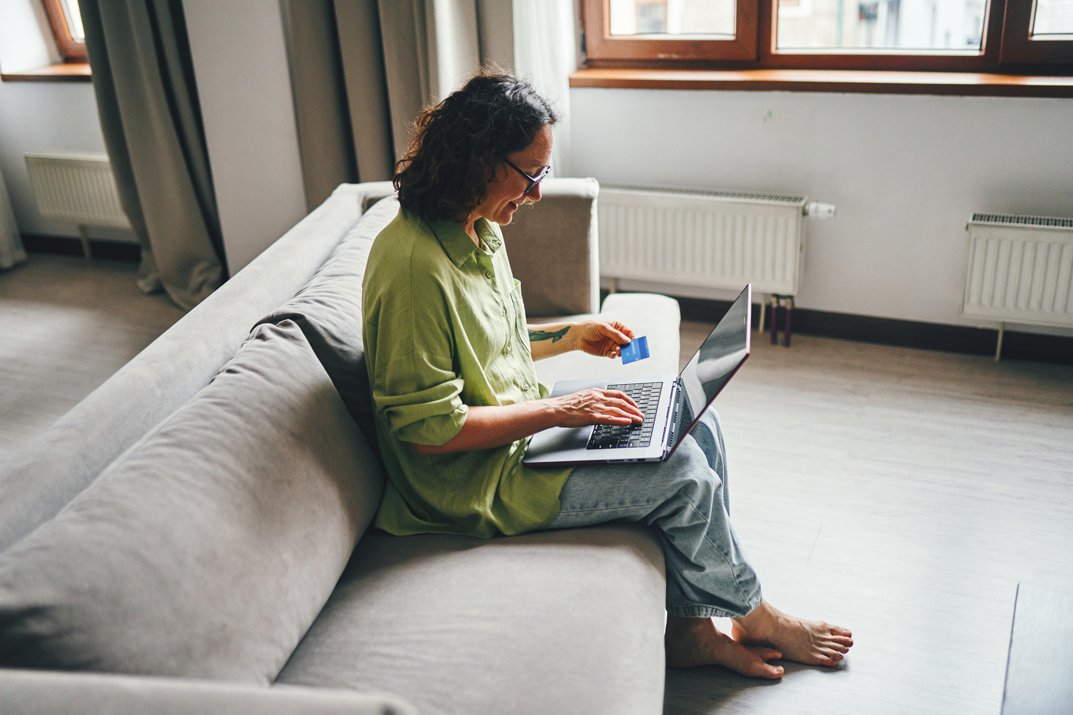 Smiling woman with credit card next to laptop