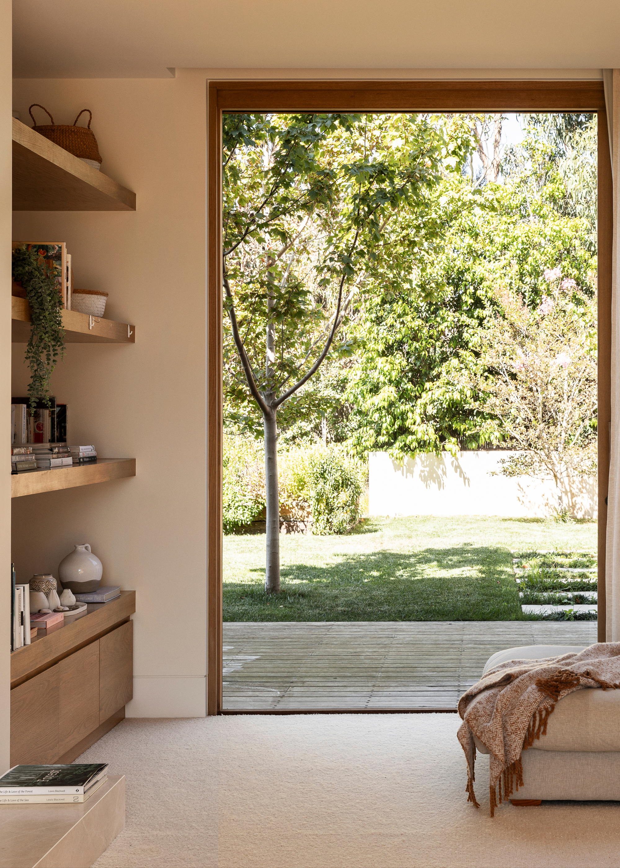 A living room with a large window opening onto a garden space with trees