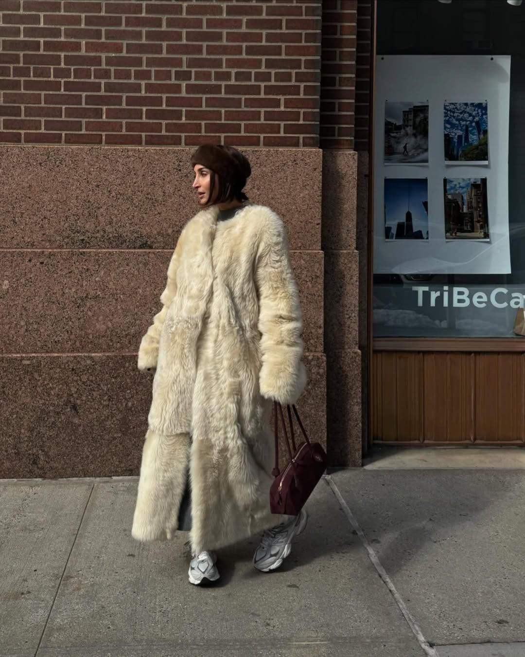 Géraldine Boublil in a furry white floor-length coat and athletic white sneakers.