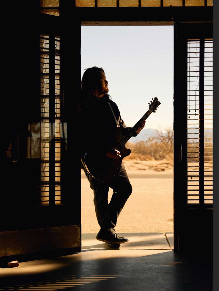 Wolfgang Van Halen silhouetted in a doorway with the desert outside