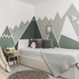 bedroom with green and grey designed wall and white bed with designed cushion