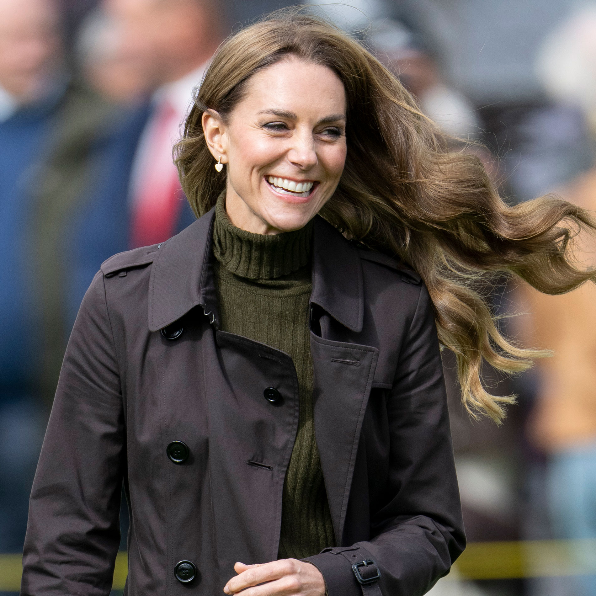 Kate Middleton wears brown skinny jeans and a green turtleneck sweater with a Burberry trench coat