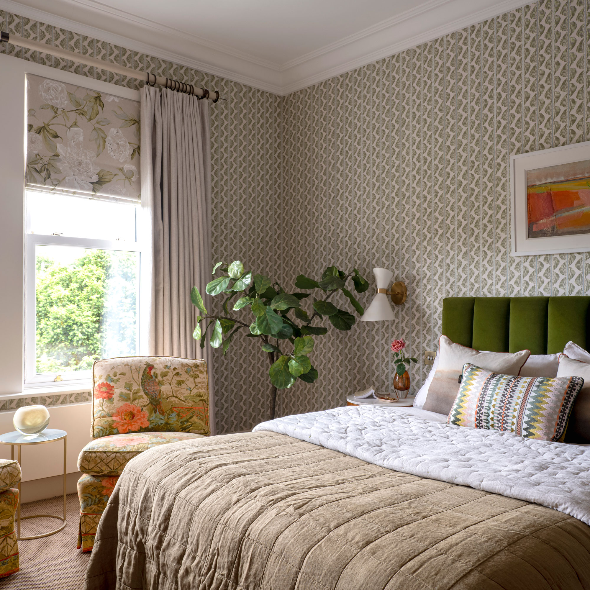 double bedroom with green upholstered headboard and patterned wallpaper