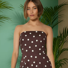 A female model wearing a brown and white polka dot strapless dress from QVC. 