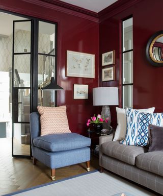 A red living room with glass partition doors and blue armchair.