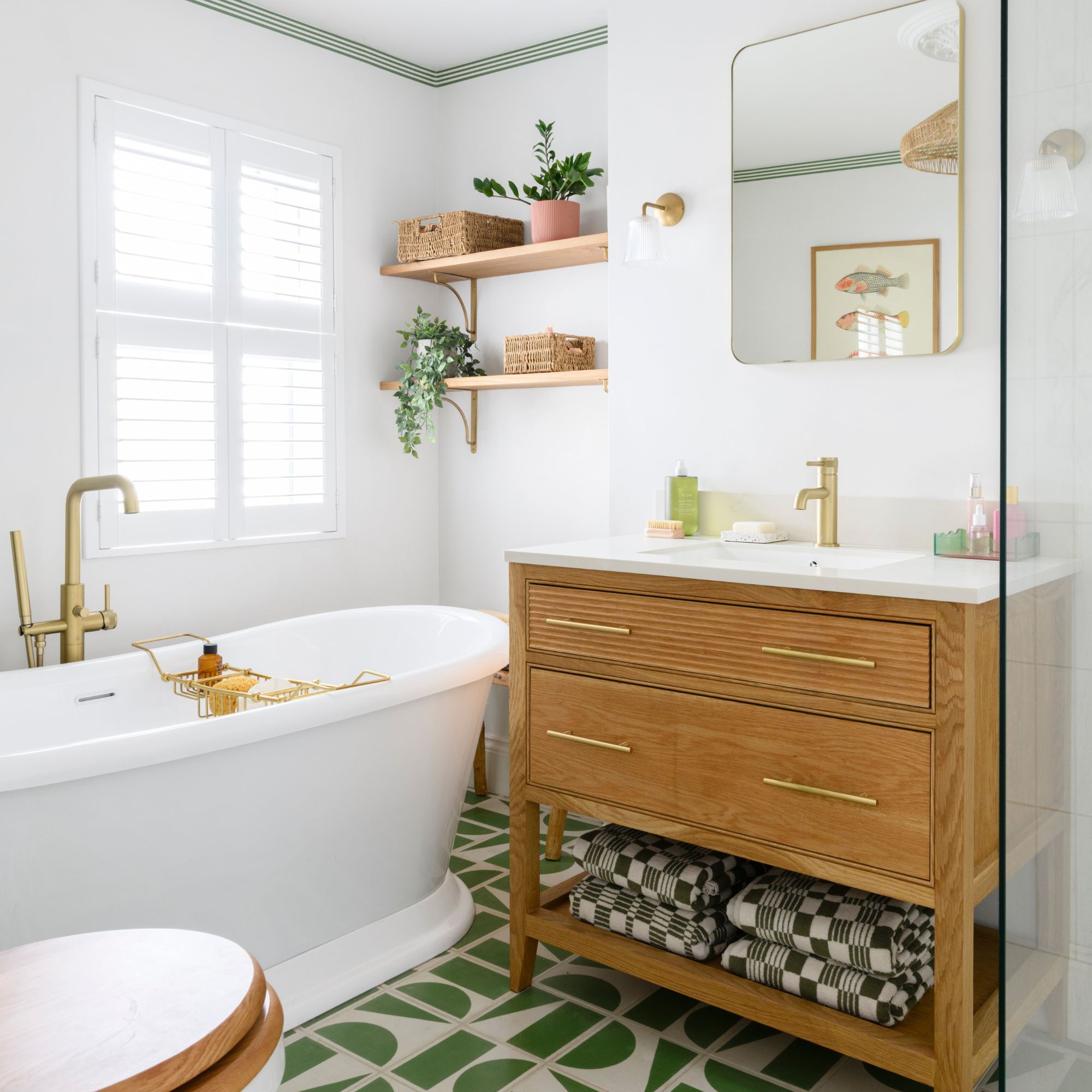 White painted bathroom with green tiled floors, a wooden sink vanity and a freestanding bath