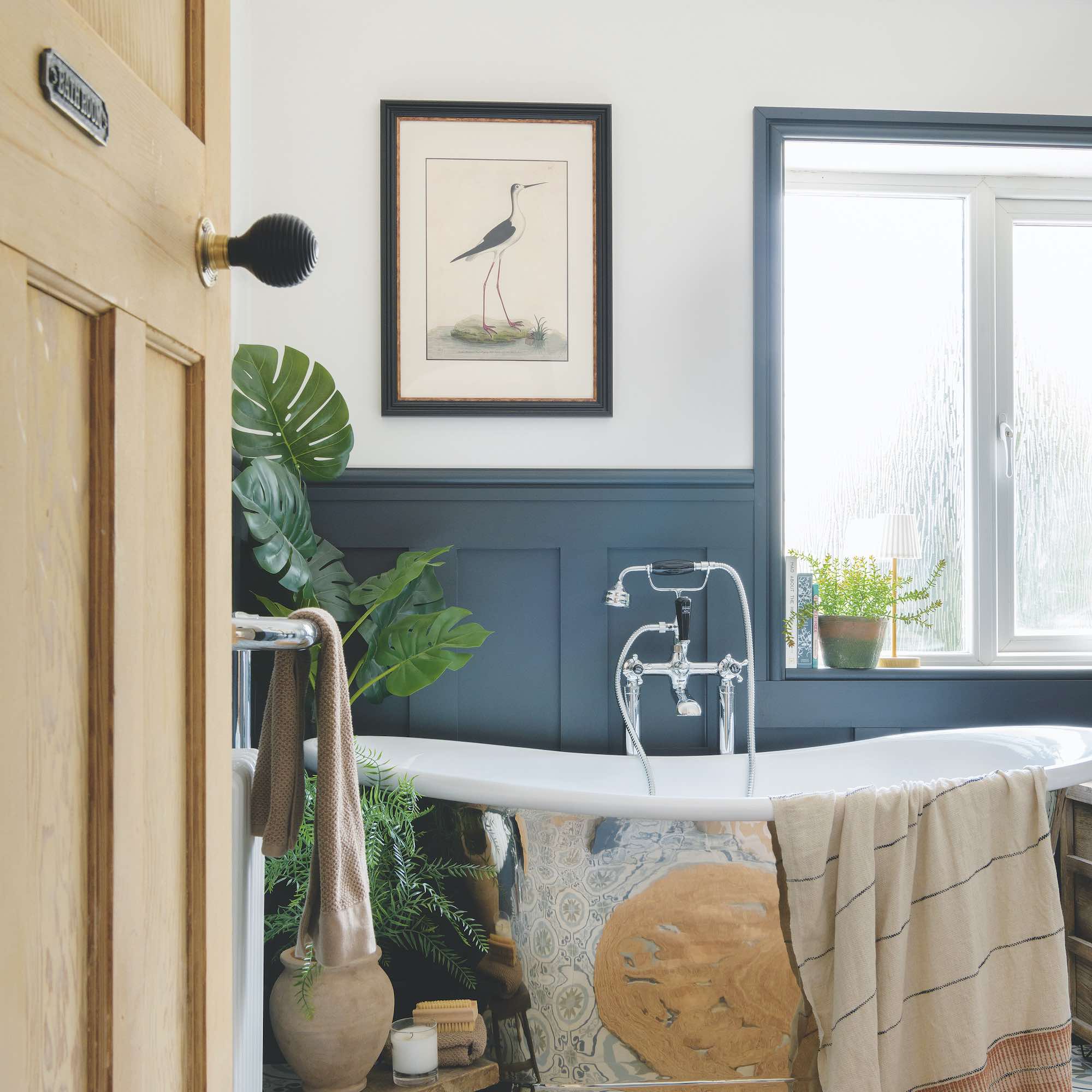 polished steel bath in blue bathroom with framed print on wall