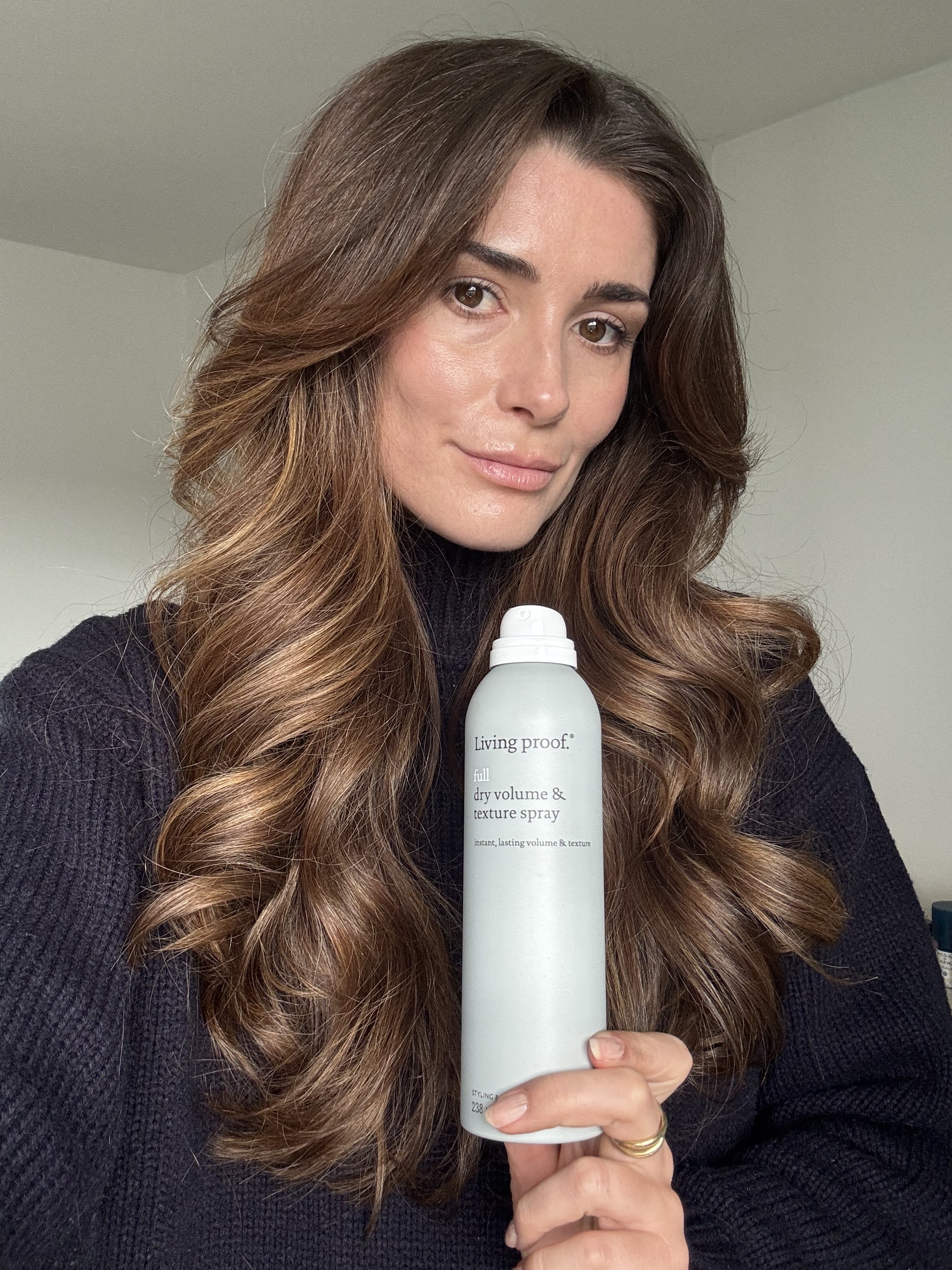Eleanor holding Living Proof Full Dry Volume and Texture Spray after styling her hair with it