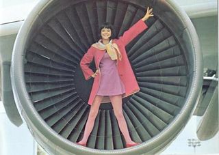 Hostess wearing pink standing in front of one of the airplanes engines