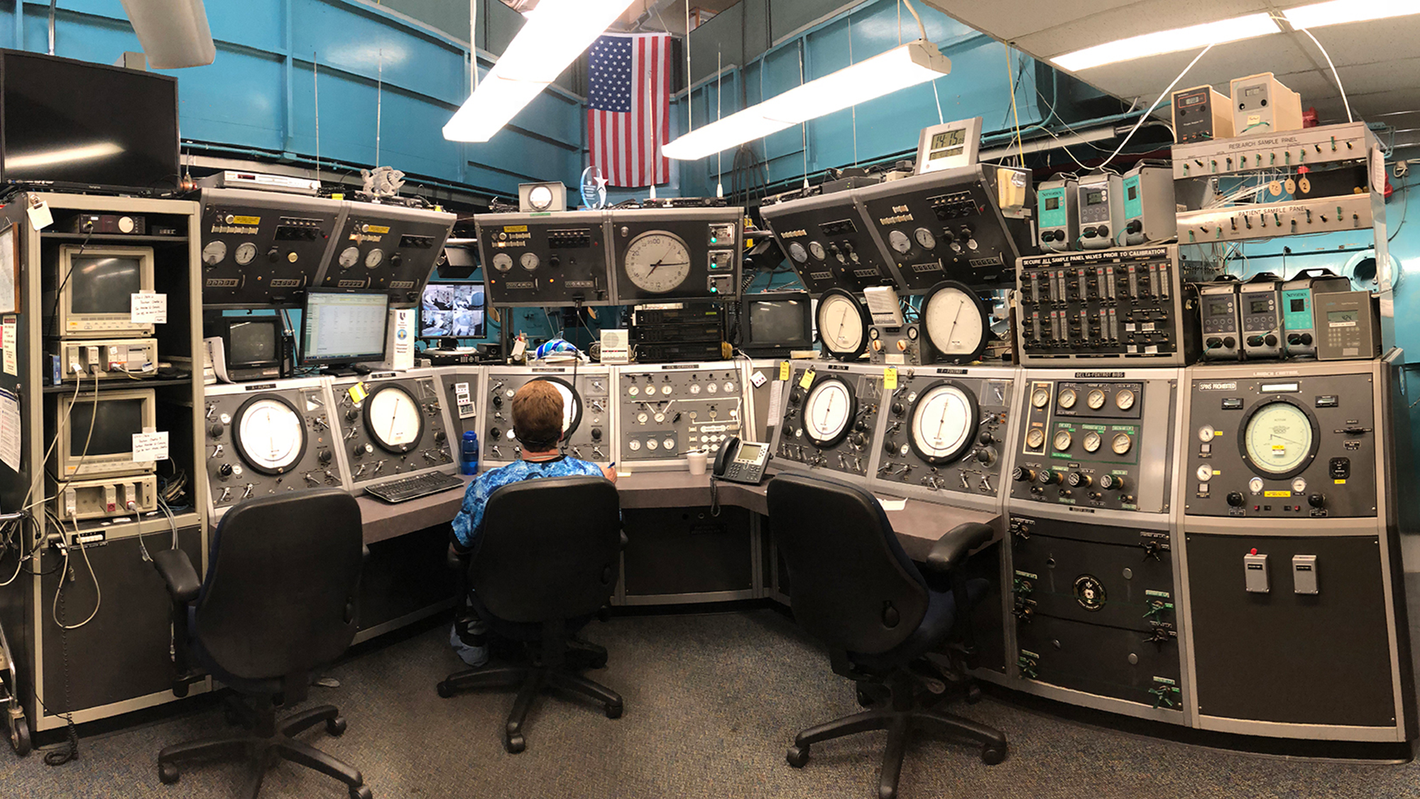 A view of someone sitting at a desk in front of a large blue tank