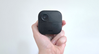 A hand holding the Blink Outdoor 4 wireless security camera