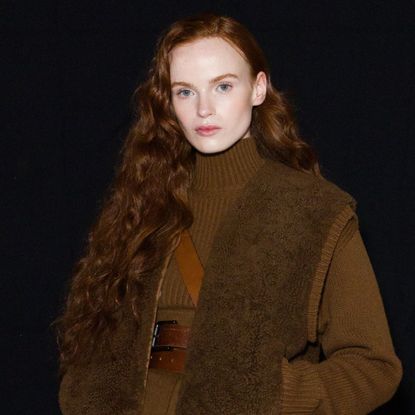 A model with long, healthy looking auburn hair looks into the camera
