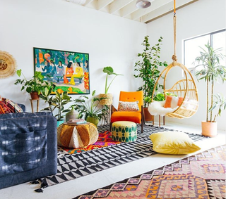 A modern living room by Justina Blakeney with colorful interior furnishings in orange, yellow and green palette, including wall art and hanging egg chair