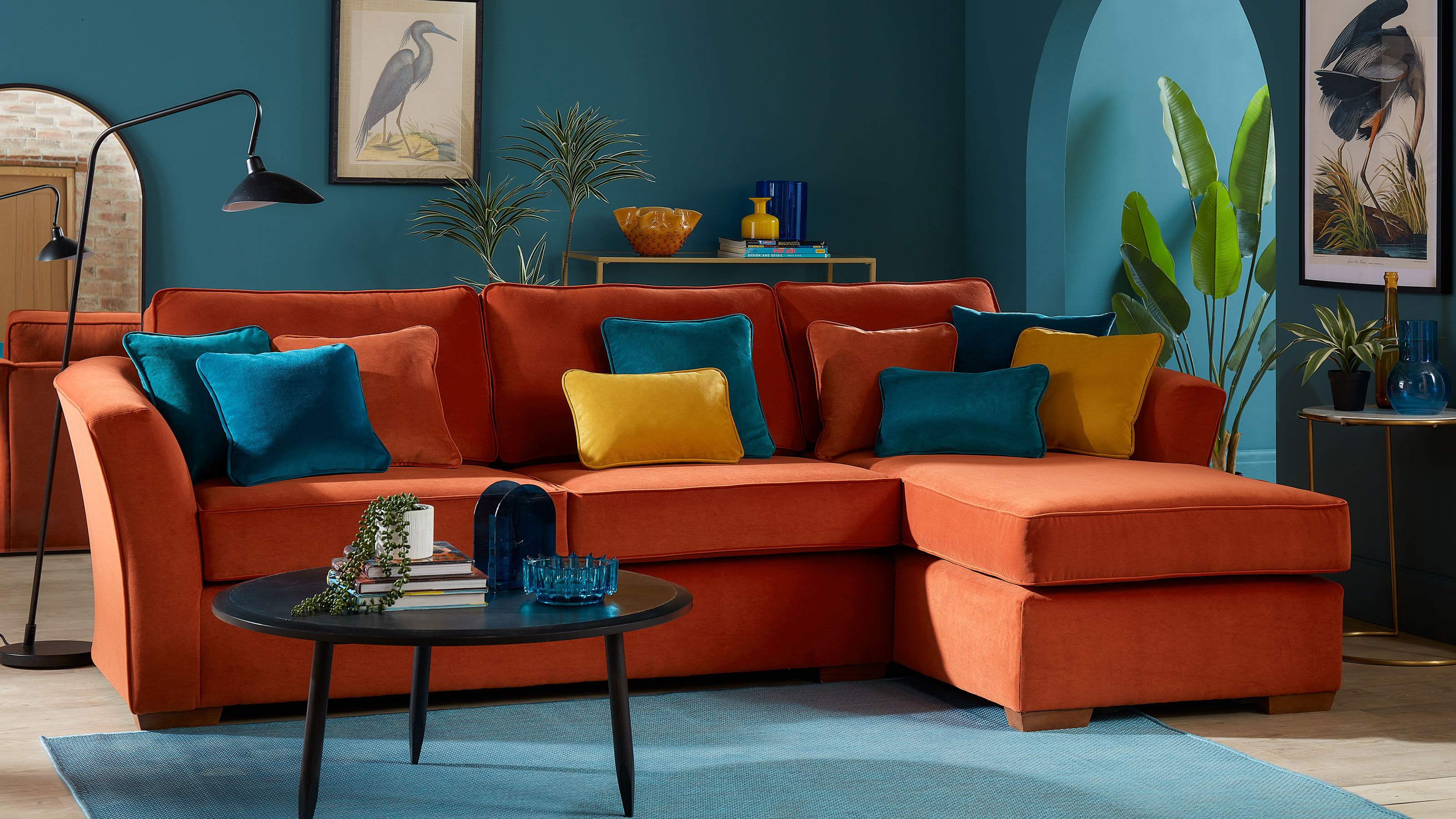Orange l-shaped sofa in turquoise living room