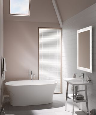 white freestanding bath in small bathroom with high vaulted ceiling, pink walls, tall window, skylight and sink with chrome legs and shelving