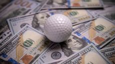 A golf ball on a pile of cash