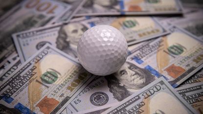 A golf ball on a pile of cash