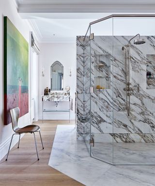 A bathroom with a large standalone marble shower, and a large painting on the wall
