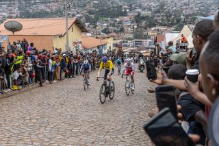 Residents gather to look at Israel Premier Techâ€™s British rider Joseph Blackmore (C), competing during the final stage of the 16h Tour du Rwanda on 25 February 2024, in Kigali. Blackmore, won the Tour of Rwanda which ended on Sunday in the capital Kigali. (Photo by Guillem Sartorio / AFP)