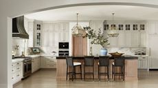 kitchen with arched opening cream cabinets wood island detail and black cooker hood
