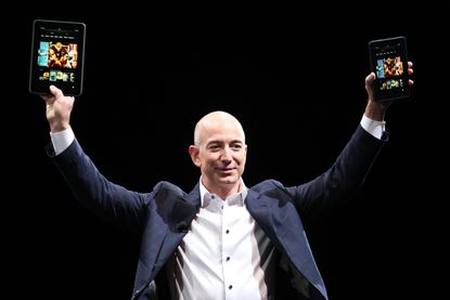 Jeff Bezos holds up Kindles
