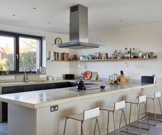 U-shaped kitchen unit in cream with four barstools and overhead hob extractor