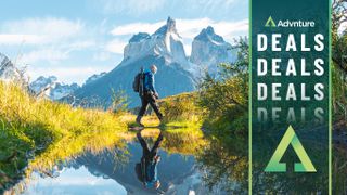 Man hiking by mountain range with reflection in lake