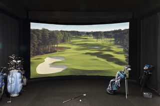 room with golf simulation, golf clubs, image on wall