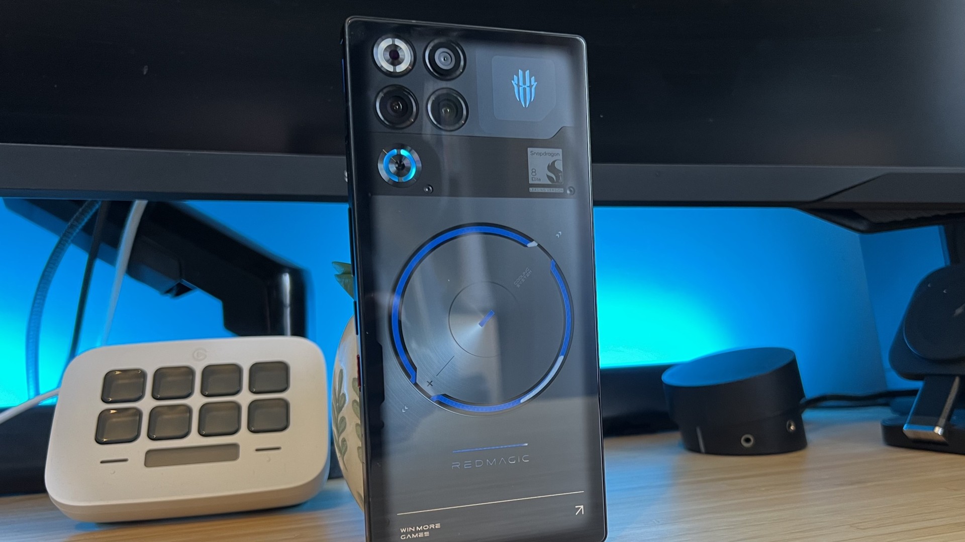 RedMagic 11S Pro gaming phone standing vertically on a wooden desk with blue backlighting