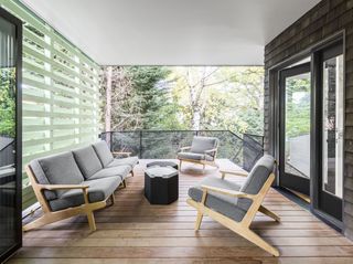 screened in porch with low grey armchairs and wood decking