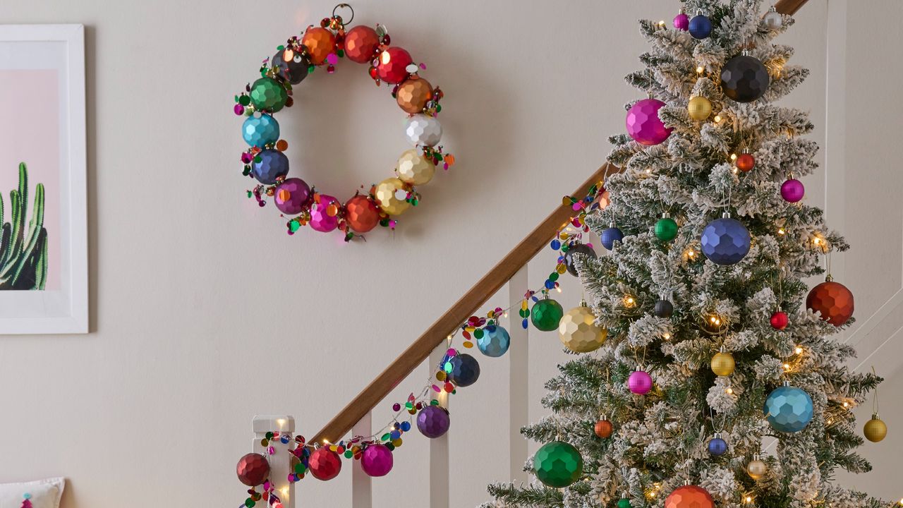 A colourfully decorated Christmas tree at the bottom of a staircase