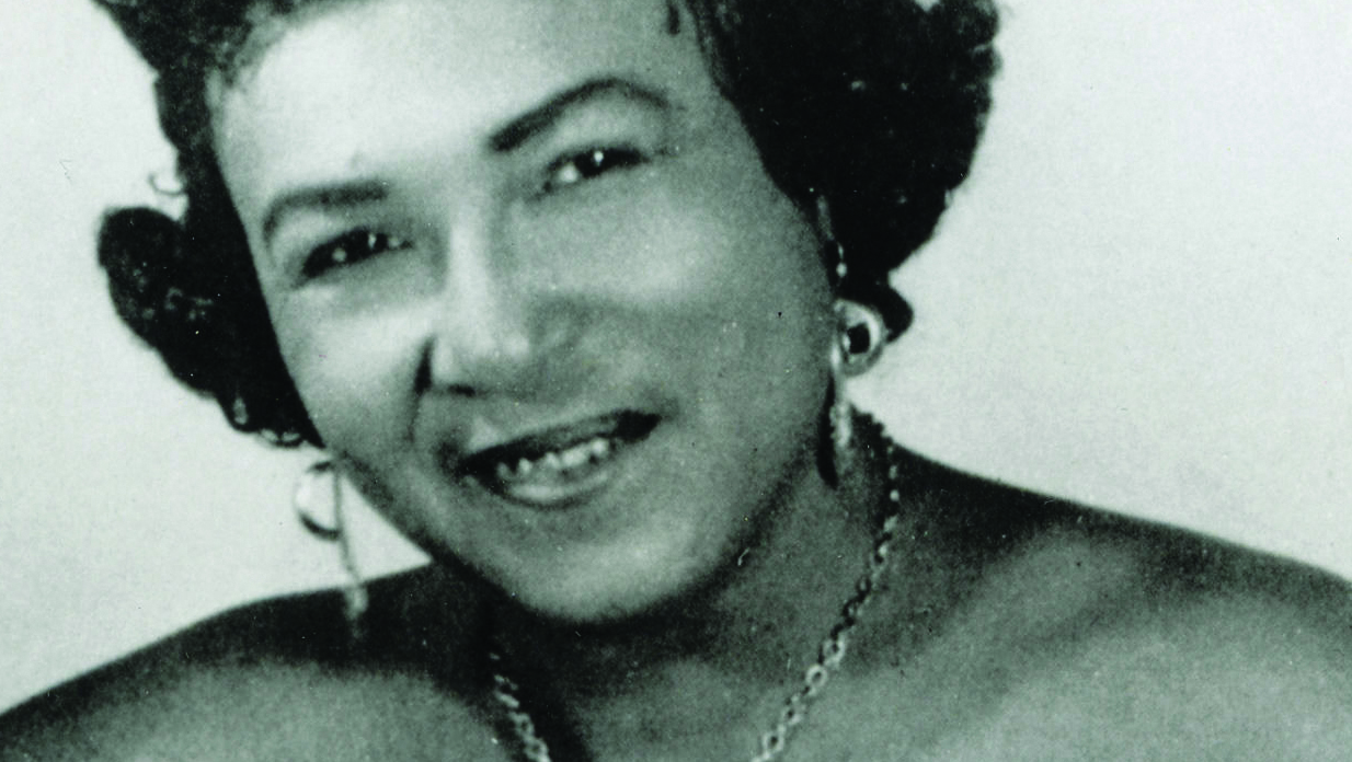 Memphis Minnie looking at the camera, wearing earrings and a necklace.