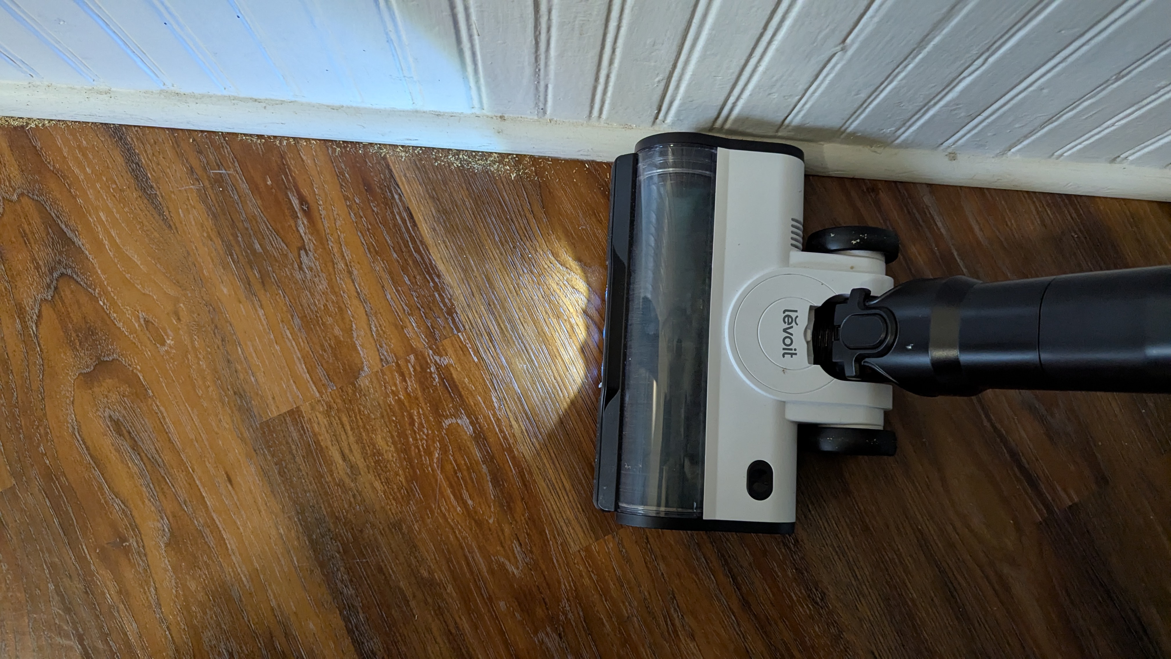 Levoit Aero vacuum being used to clear debris from a wooden floor