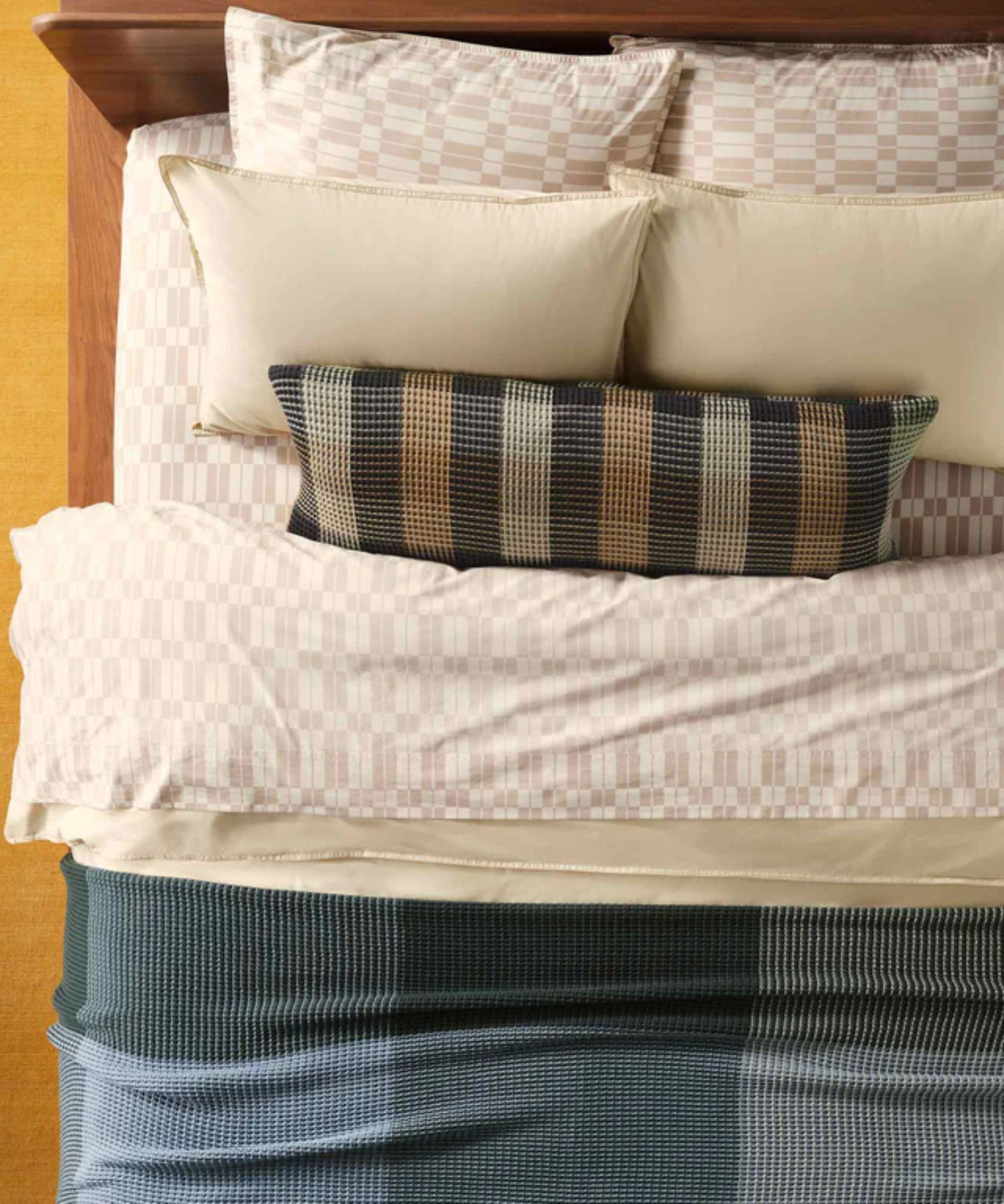 Top-view shot of bed with geometric bedding, throw pillow and throw