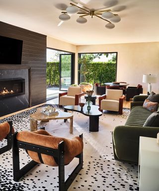 A large living room with a dark fireplace, a black and white area rug, and colorful furniture