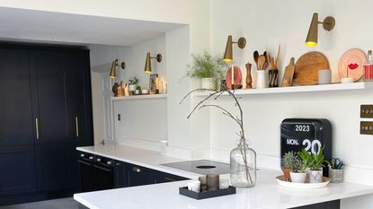 Charcoal grey kitchen with white worktops and upstands and an open shelf running along the wall