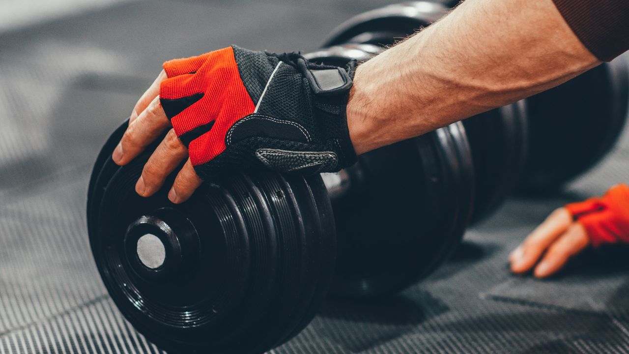 Best gym gloves: person moving dumbbells wearing gym gloves