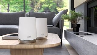 Netgear Orbi RBK752 double pack displayed on a wooden coffee table in a decorated living space.