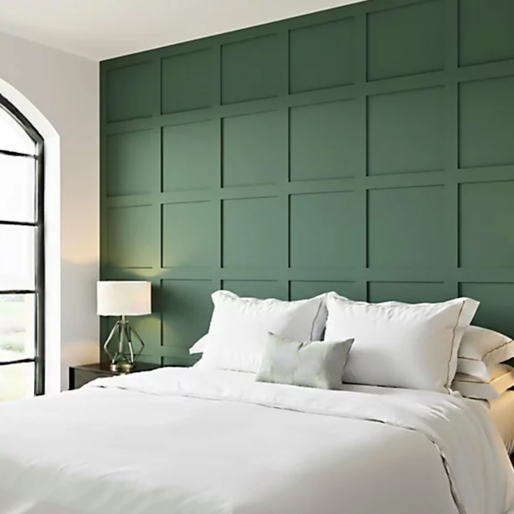 Green square shaker panelled wall behind a white double bed
