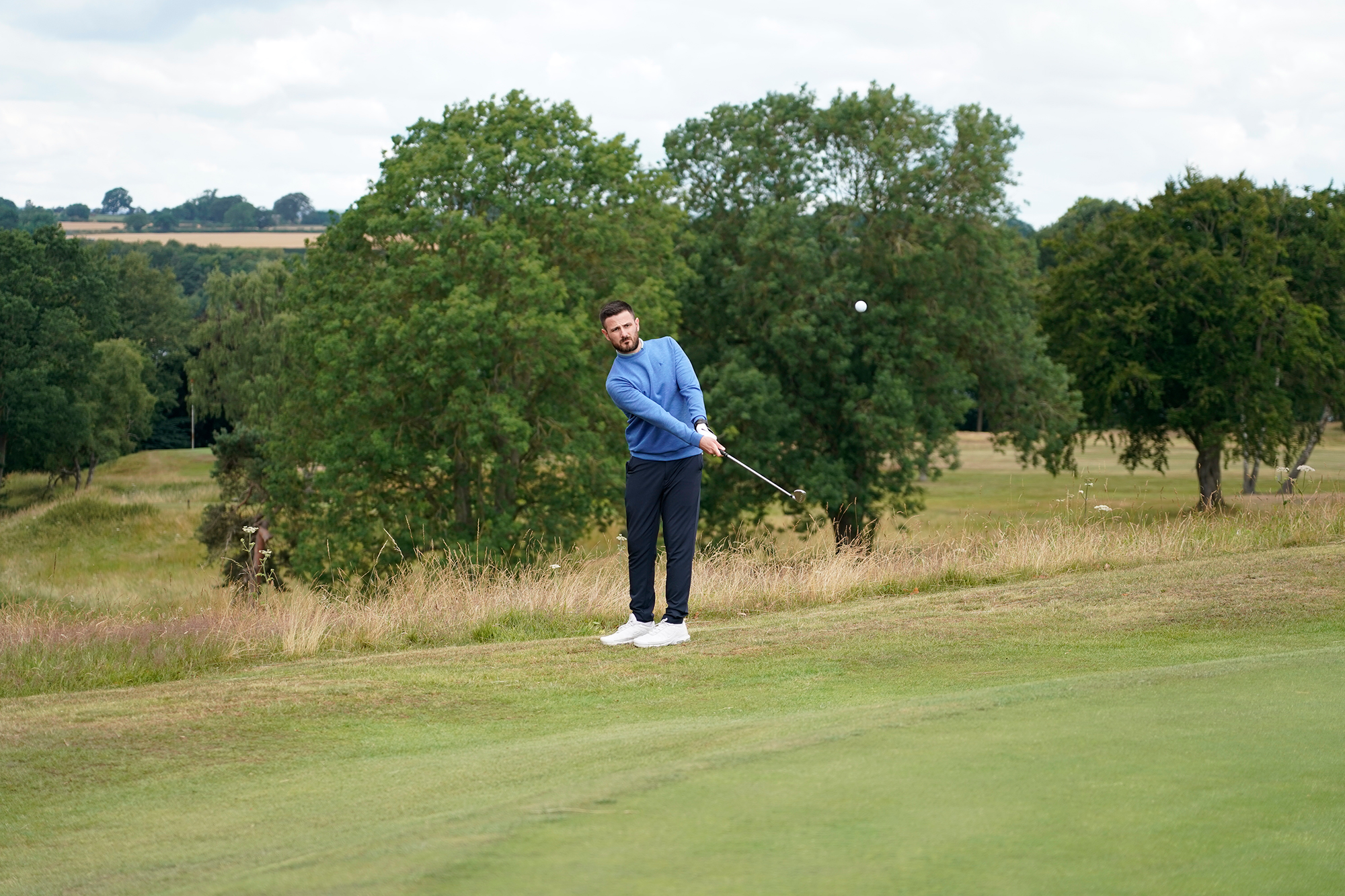Barry Plummer hitting a chip shot from off the back of the 8th green at Sand Moor Golf Club, holding the finish position as the ball is in flight towards the green