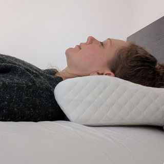 A woman in a green jumper with her head on a pillow