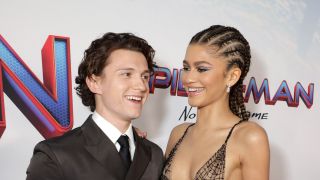 Zendaya and Tom Holland smiling on the red carpet of Spider-Man: No Way Home.